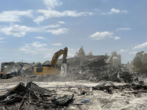 Koparka wyburzeniowa pracująca na placu rozbiórki budynku.