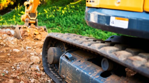 Detailní záběr na pásy minirýpadla pracujícího na staveništi.