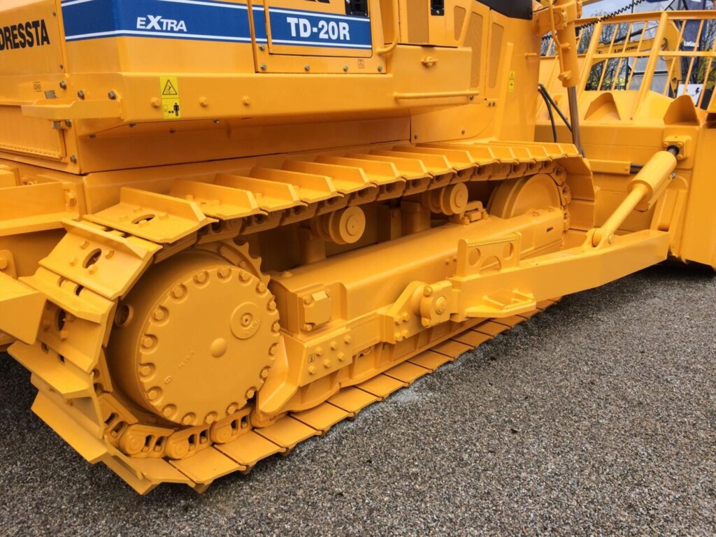 Žlutý pásový podvozek stavebního stroje typu buldozer.