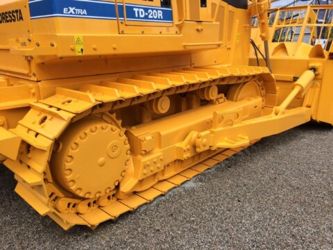 Žlutý pásový podvozek stavebního stroje typu buldozer.