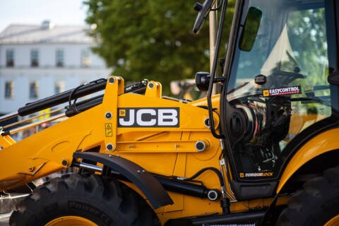 Detailní záběr na žlutý JCB zpětný nakladač stojící venku.