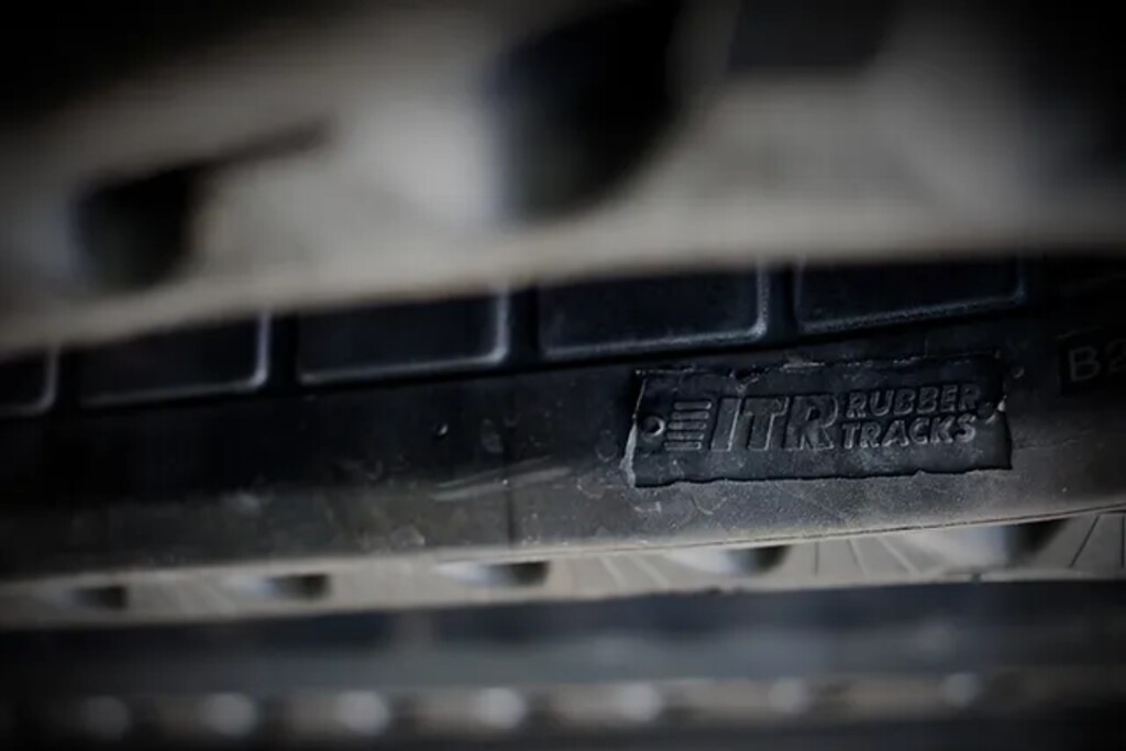 Obrázek zobrazuje detail gumového pásu s nápisem „ITR Rubber Tracks“.