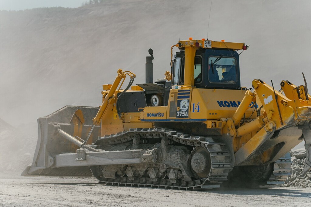 Buldozer Komatsu D375A s pásovým podvozkem pracující na staveništi v prašném prostředí.
