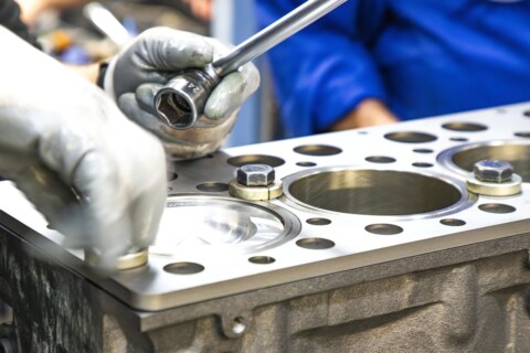 Pracovník používá klíč k dotažení součástí motoru.